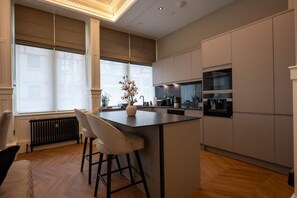 Eine moderne Küche mit Kochinsel, Barhocker und einem Essbereich mit Heizkörper.