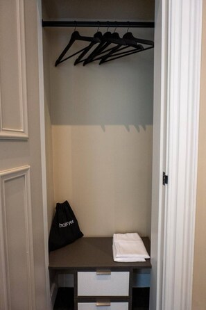 A walk-in closet with a hanging rod, a black bag, and a folded white towel. - Grand Leith Luxe: Jacuzzi & Cinema Room (Edinburgh)