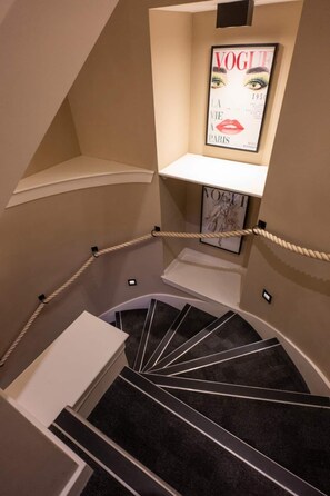 Eine Wendeltreppe mit Seilbarriere, einer gerahmten Zeitschriftencover und einem weißen Regal.