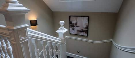 A staircase with a white balustrade, a skylight, and a wall-mounted light fixture.