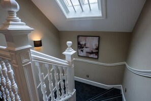 A staircase with a white balustrade, a skylight, and a wall-mounted light fixture. - Sophisticated Urban Living| Sleek 4-Bedroom Home (Edinburgh)