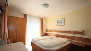 A hotel room with a bed, bedside table, and a desk with a chair.