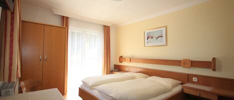 A hotel room with a bed, bedside table, and a desk with a chair.