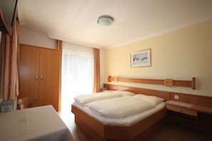 Quarto de hotel com cama, mesa de cabeceira e escrivaninha com cadeira.