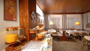 A dining area with wooden furniture, a buffet setup, and a patterned floor.