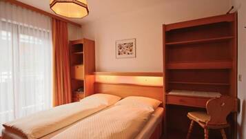 Een slaapkamer met een bed, bureau, stoel en kledingkast.