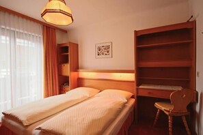 A bedroom with a bed, a desk, a chair, and a wardrobe.