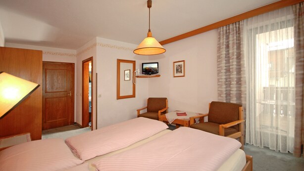 A hotel room with two beds, a desk, a chair, a television, and a window with curtains.