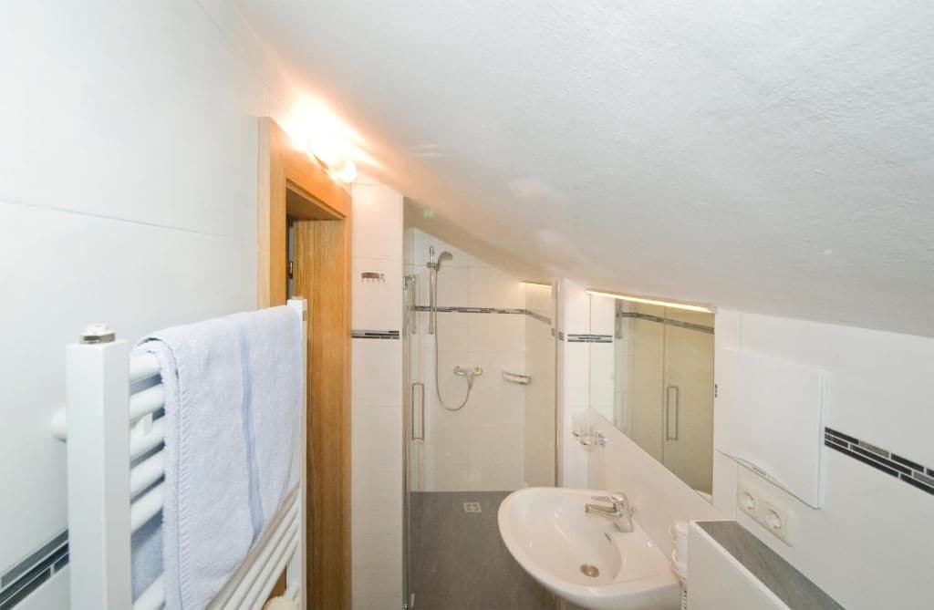Een kleine badkamer met een douche, wastafel en handdoekhouder.