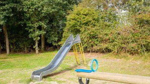 Een speeltuin met een glijbaan en schommels in een park.