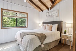 A bedroom with a bed, a nightstand, a window with blinds, and a wall-mounted artwork. - Lakeside Getaway at Innsbrook by Sarah Bernard (Innsbrook)