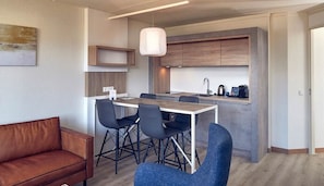 A modern kitchen with a dining area, featuring a central island, a hanging light fixture, and built-in cabinets. - Stay on Ameland Near Beach – Hotel Comfort, Dining & Nature Walks - 4 Units (Nes)