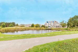 A hotel with a large building, a pond, and a pathway. - Stay on Ameland Near Beach – Hotel Comfort, Dining & Nature Walks - 4 Units (Nes)