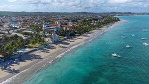 Un pueblo costero con una playa, aguas turquesas cristalinas y varios barcos.