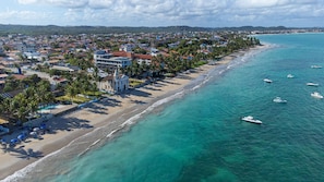 Eine Küstenstadt mit Strand, klarem türkisblauem Wasser und mehreren Booten.