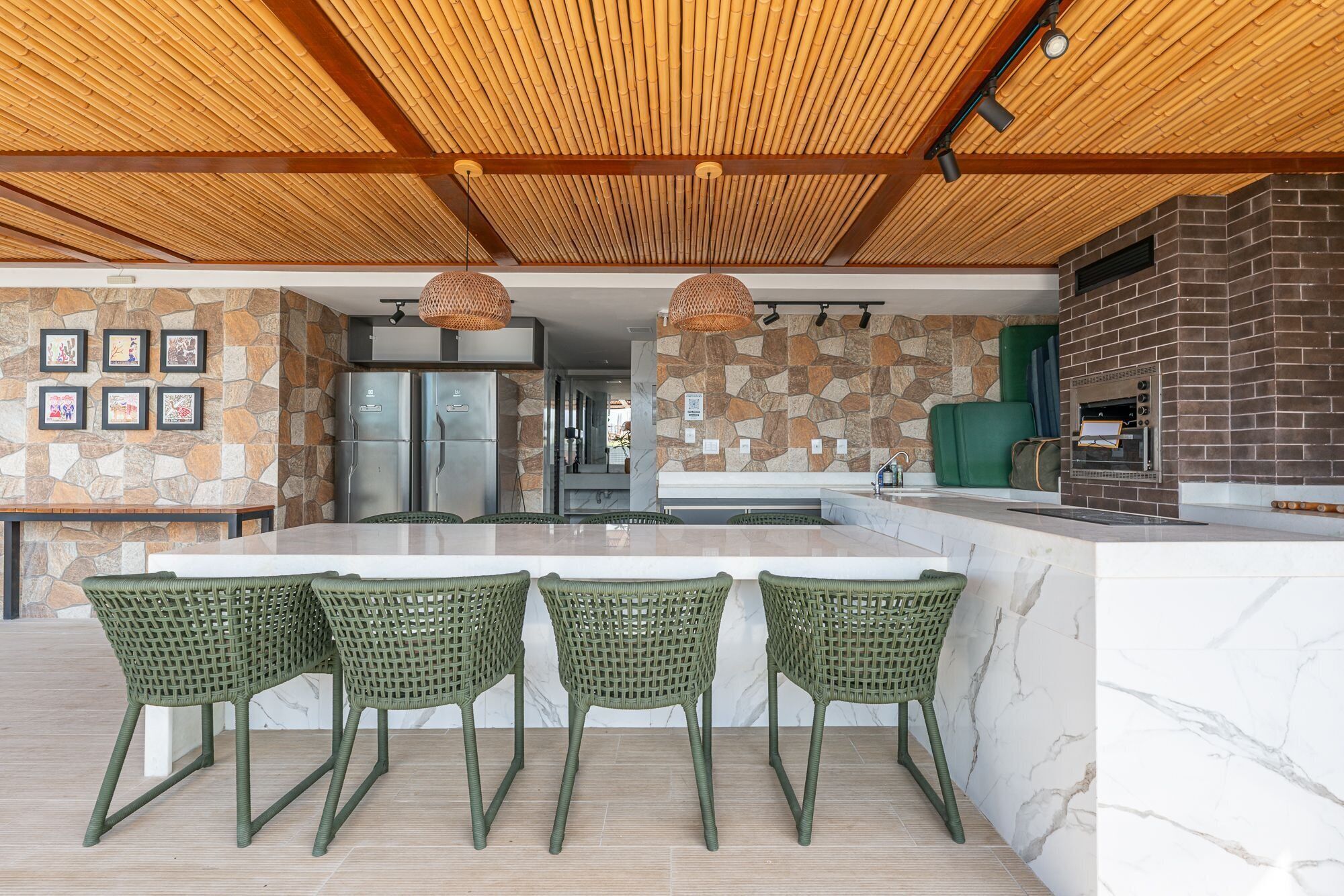 Una cocina moderna con un salpicadero de pared de piedra, horno empotrado y una isla grande con taburetes de bar.