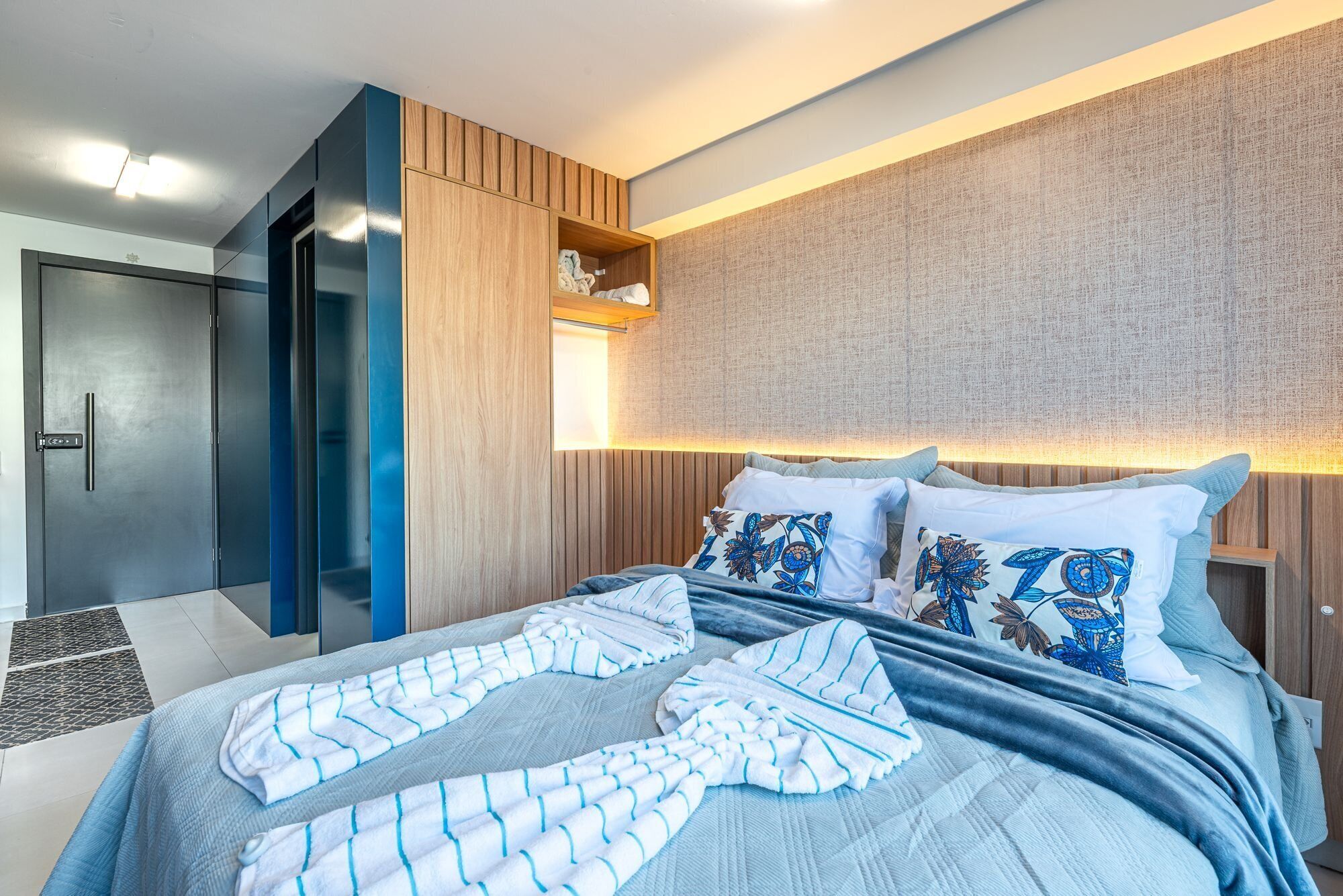 Une chambre d’hôtel moderne équipée d’un lit, d’une armoire et d’un placard intégré avec des étagères.