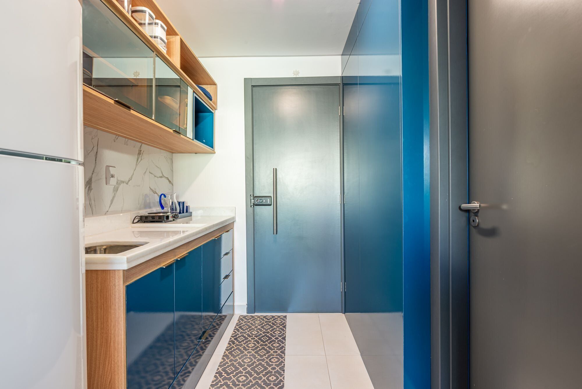 Un baño moderno con cabina de ducha de vidrio, pared con mosaicos de mármol y lavamanos empotrado con encimera.