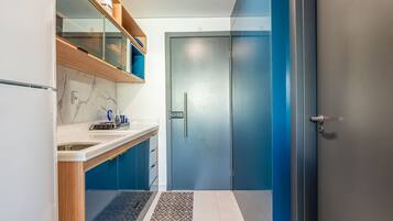 Un baño moderno con cabina de ducha de vidrio, pared con mosaicos de mármol y lavamanos empotrado con encimera.