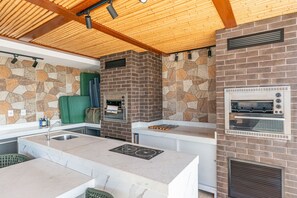 Uma cozinha moderna com painel de pedra, forno embutido e teto de madeira.