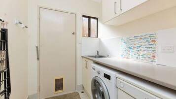 A laundry room with a washing machine, a sink, and a door.