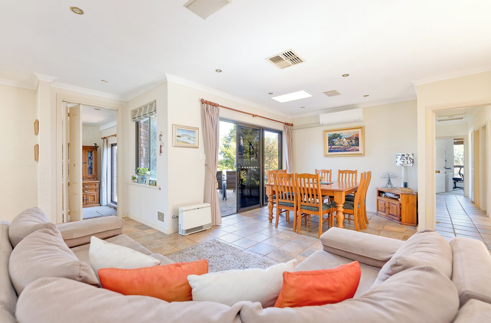 A spacious living area with a sofa, a dining table with chairs, and a view through a glass door to an outdoor patio.