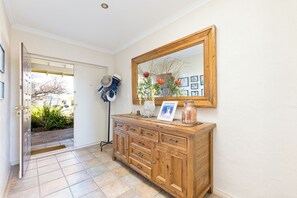 A hallway with a wooden cabinet, a mirror, and a door leading outside. - Comfortable 4-bedroom fully-furnished home near train & Carine Open Space (Duncraig)