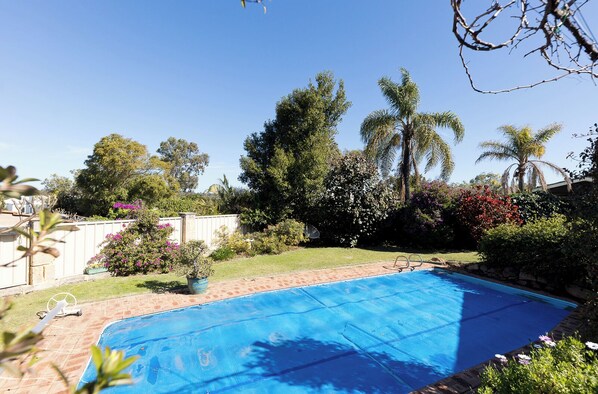Ein Garten mit einem Swimmingpool, umgeben von Bäumen und Sträuchern.