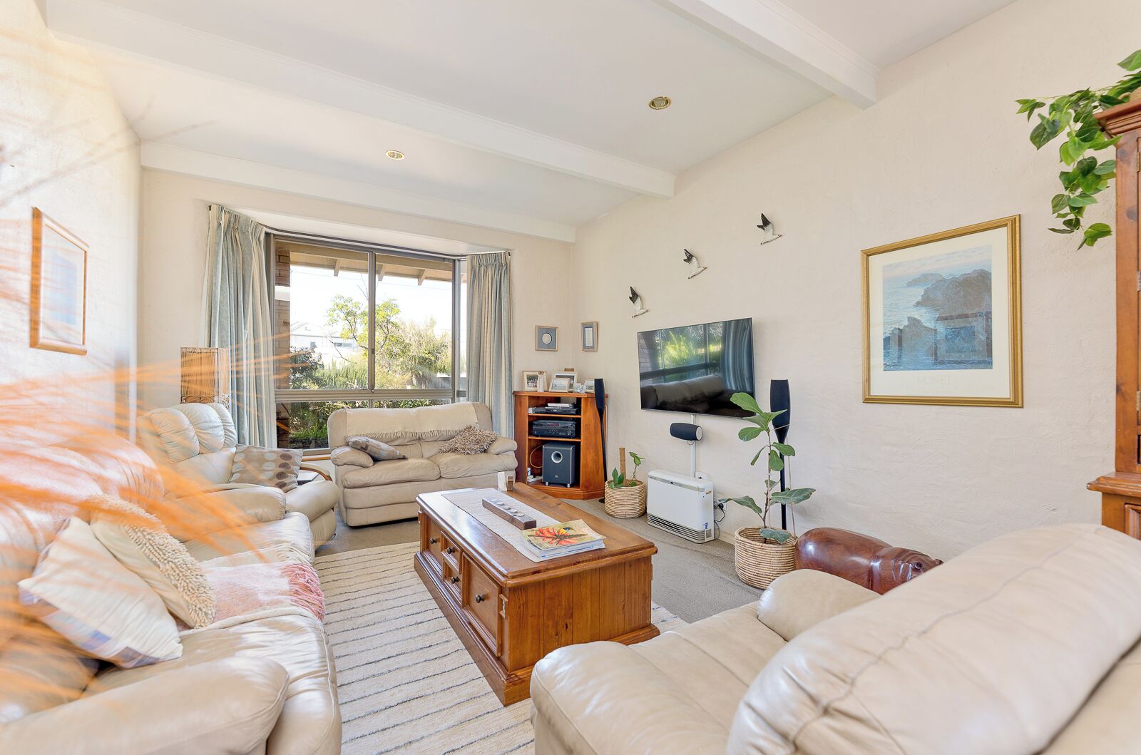 A spacious living room with a large window, a flat-screen TV, and a fireplace.