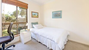 Una camera da letto con un letto, una scrivania, una sedia e due quadri appesi al muro.