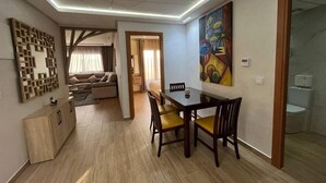 A modern living room with a dining area, a sofa, a coffee table, and a painting on the wall.