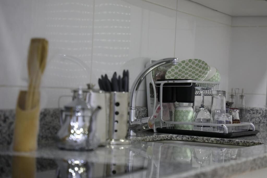 A kitchen counter with a dish rack, a coffee maker, and a knife holder.