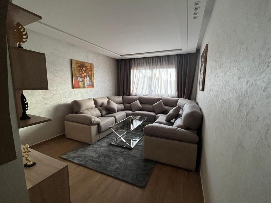 Una sala de estar moderna con un sofá modular, una mesa de centro de vidrio y un cuadro en la pared.