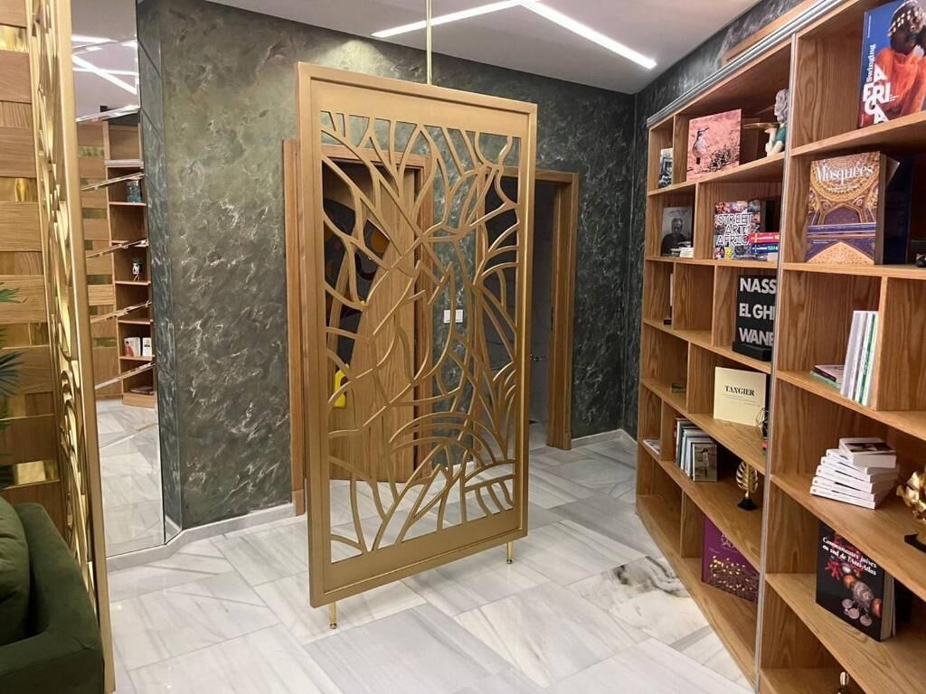 A room with a wooden bookshelf, a decorative screen, and a tiled floor.