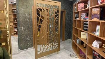 A room with a wooden bookshelf, a decorative screen, and a tiled floor.