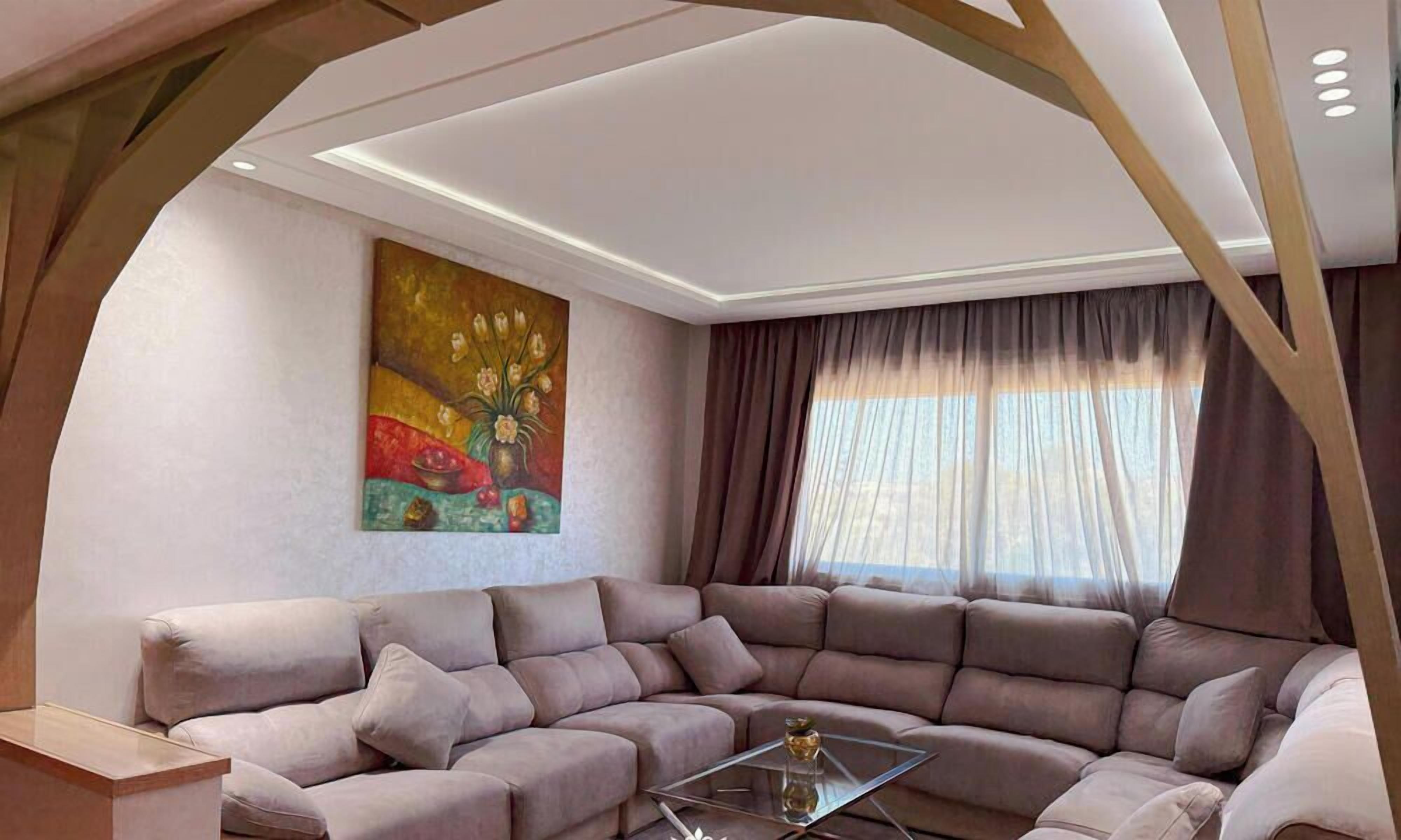 A modern living room with a sectional sofa, a glass coffee table, and a painting on the wall.