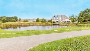 Et hotel med en stor bygning, et spejlende vand og en sti.