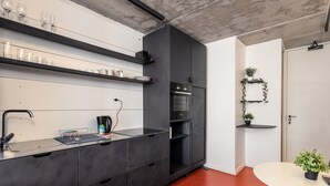 A modern kitchen with black cabinetry, a built-in oven, and a red floor. - The Urban Nest by Ctha (Cape Town)