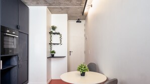 A compact kitchen with a Bosch oven, a white door, and a small dining area with a round table and two chairs. - The Urban Nest by Ctha (Cape Town)