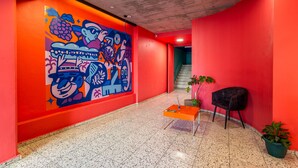 A hallway with a vibrant mural, a staircase, a small table with a plant, and a black chair. - The Urban Nest by Ctha (Cape Town)