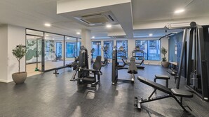 A gym with various exercise equipment, large windows, and a potted plant. - Luxury Living in Circa Illovo by Ctha (Johannesburg)
