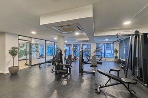 A gym with various exercise equipment, large windows, and a potted plant. - Luxury Living in Circa Illovo by Ctha (Johannesburg)