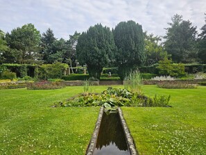 A garden with a central pond, surrounded by well-maintained grass and various plants. - Family Retreat w/Scenic Views, Onsite Dining | Nature Trails & Wellness Access (Wageningen)