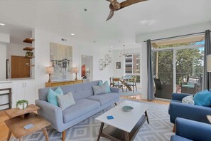 Uma sala de estar moderna com um sofá, mesa de centro e um espaço de jantar com cadeiras.