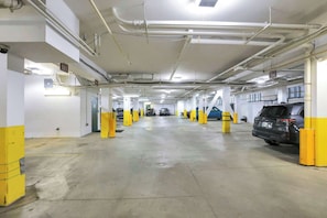 Garagem de estacionamento em vários níveis, com pisos de concreto e mourões de segurança amarelos.