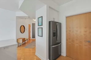 Cozinha moderna com geladeira de aço inoxidável, piso de madeira e porta de madeira.