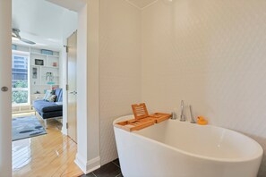 Ein modernes Badezimmer mit einer freistehenden Badewanne, einem Holztablett für das Bad und einem Quietscheentchen.