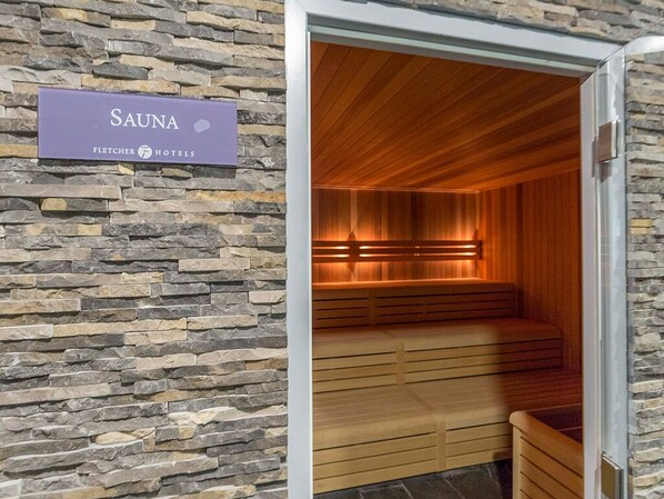 Sauna, jossa on puiset lauteet ja kiviseinä.