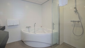 Een moderne badkamer met een vrijstaand bad, een douchecabine van glas en een handdoekrek.