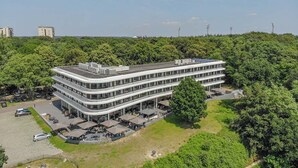 Un edificio de varios pisos con techo plano, rodeado de vegetación.